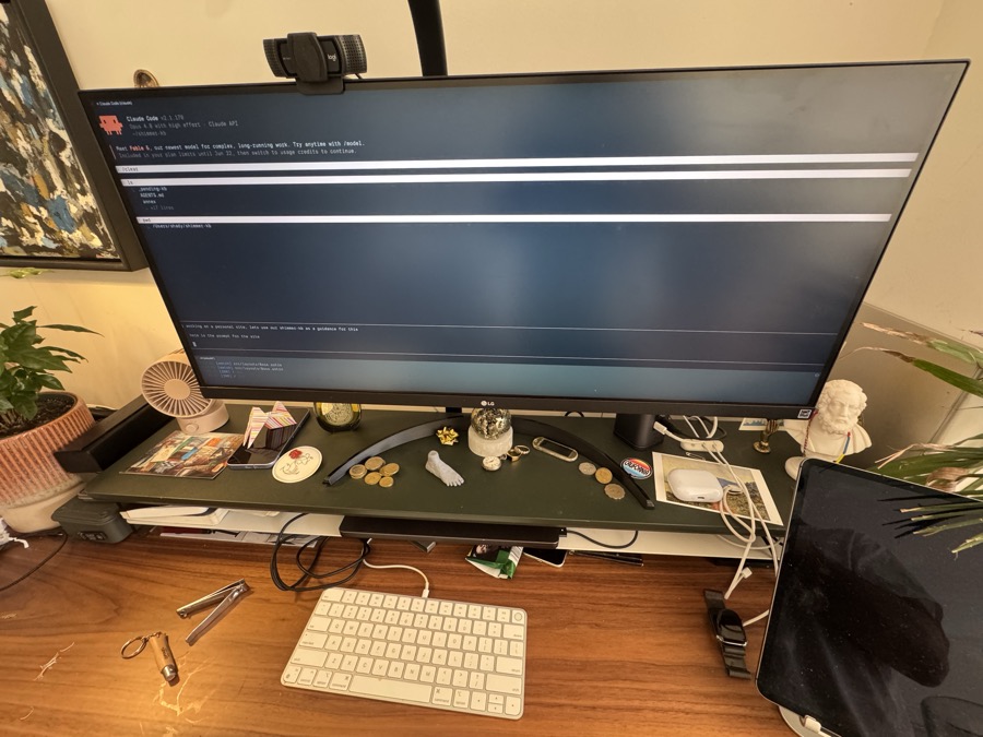 Shady's desk — an ultrawide display, curios, plants, a marble bust